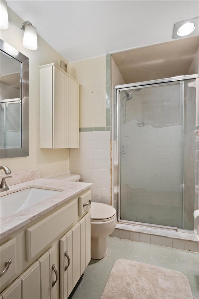 bathroom featuring a stall shower, vanity, tile walls, and tile patterned floors