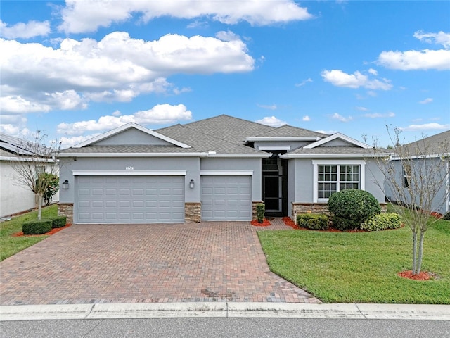 view of front facade featuring a garage, decorative driveway, a front lawn, and stucco siding