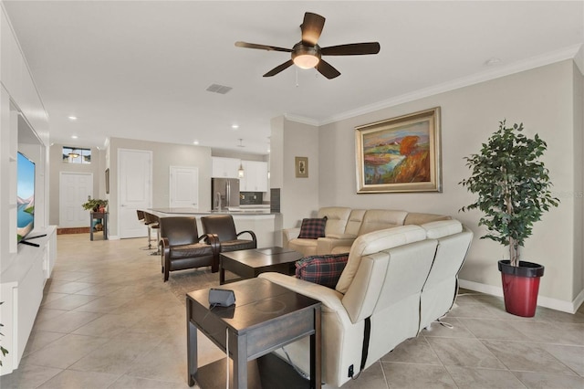 living room featuring light tile patterned floors, visible vents, ornamental molding, a ceiling fan, and baseboards