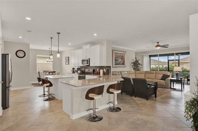 kitchen with appliances with stainless steel finishes, a kitchen breakfast bar, a peninsula, light countertops, and pendant lighting