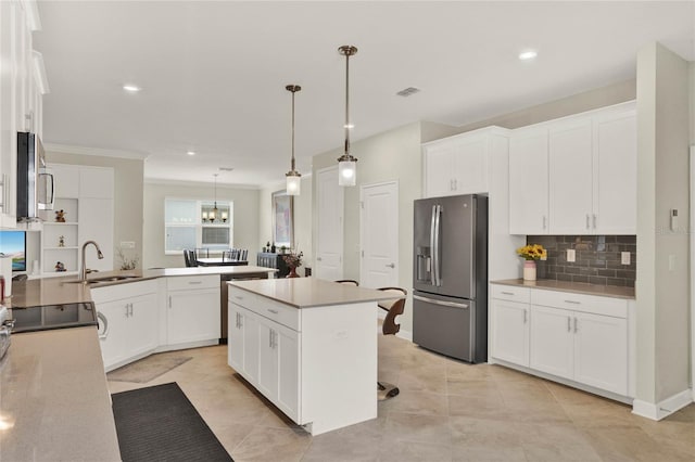 kitchen with hanging light fixtures, appliances with stainless steel finishes, light countertops, and white cabinetry