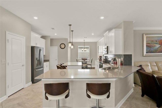 kitchen with a breakfast bar area, stainless steel appliances, light countertops, pendant lighting, and a sink