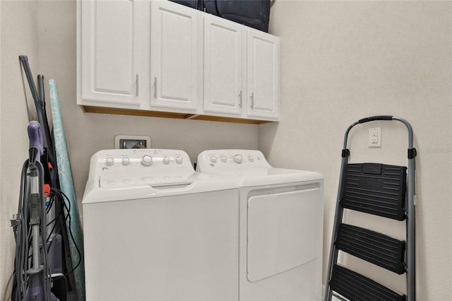 clothes washing area with washer and dryer and cabinet space