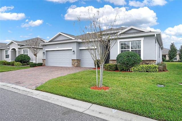 ranch-style home with stone siding, decorative driveway, an attached garage, and stucco siding