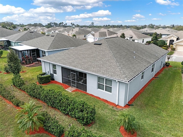 back of house with a yard, a shingled roof, a residential view, and stucco siding