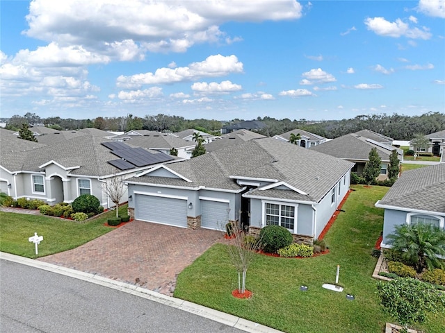 view of front facade featuring a garage, a residential view, decorative driveway, and a front yard