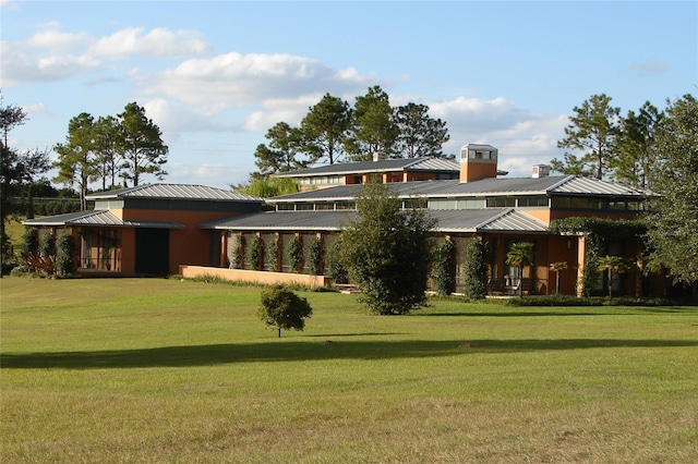 back of property featuring a standing seam roof, metal roof, and a lawn