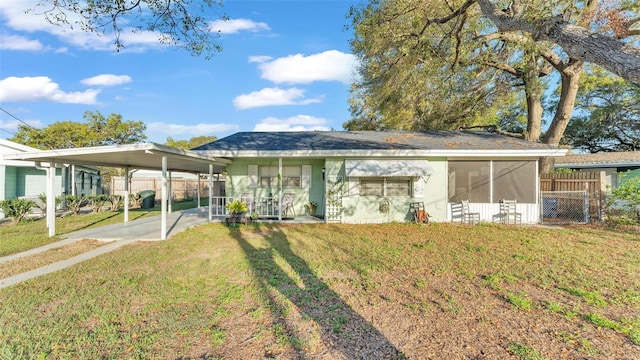 exterior space featuring a sunroom, fence, a carport, driveway, and a front lawn