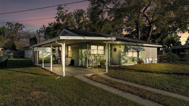 view of front of home featuring a yard, an attached carport, and fence