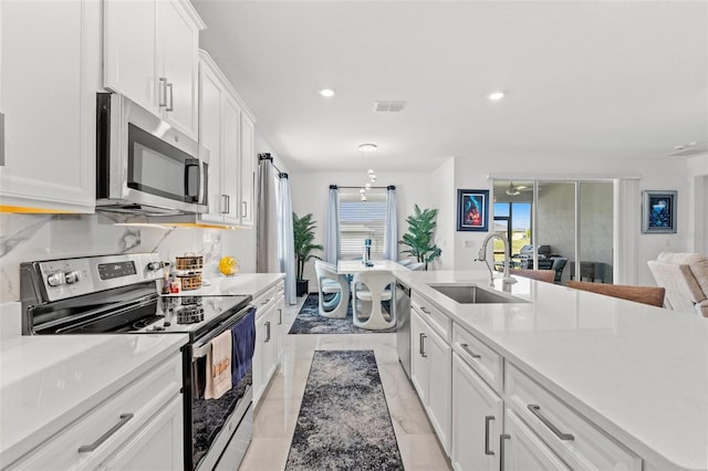 kitchen with stainless steel appliances, a sink, visible vents, white cabinetry, and tasteful backsplash