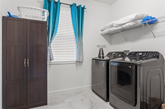 laundry area featuring marble finish floor, washer and clothes dryer, cabinet space, and baseboards