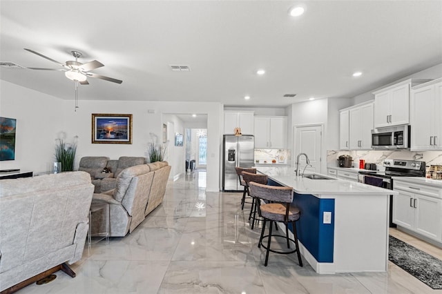 kitchen with appliances with stainless steel finishes, visible vents, a sink, and a kitchen breakfast bar