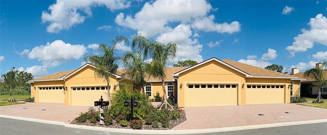 ranch-style house featuring a garage, decorative driveway, and stucco siding