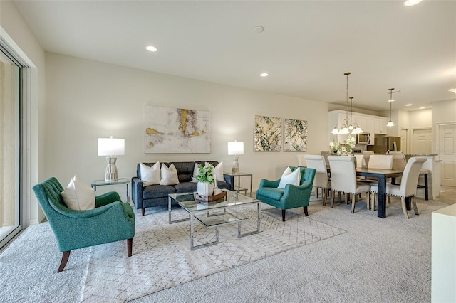 living area featuring recessed lighting, light carpet, and an inviting chandelier