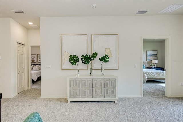 hallway with light carpet, baseboards, and visible vents