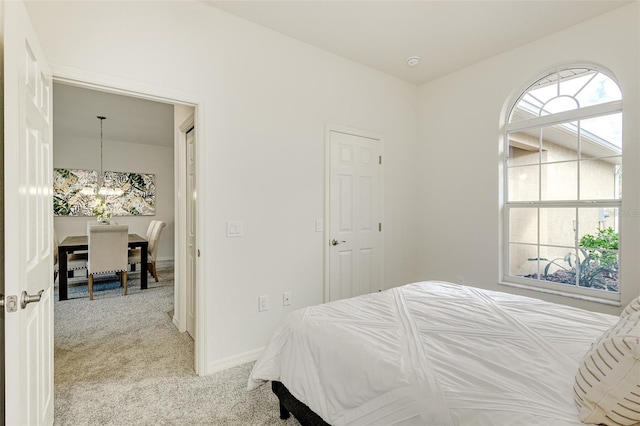 bedroom featuring light colored carpet, baseboards, and an inviting chandelier