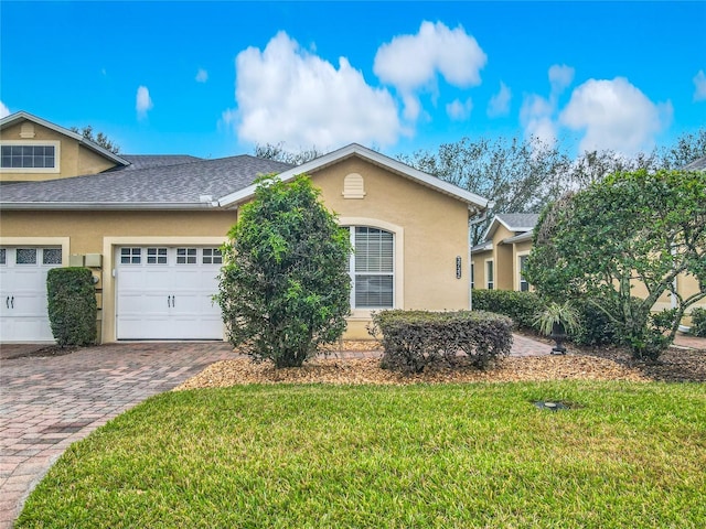 view of front of property featuring a front yard, decorative driveway, and stucco siding