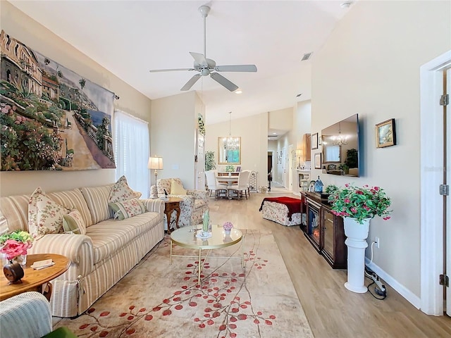 living room with baseboards, visible vents, light wood-style floors, high vaulted ceiling, and ceiling fan with notable chandelier