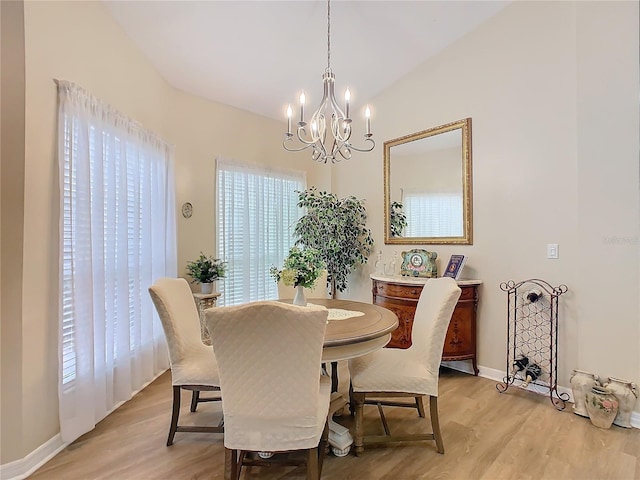 dining area featuring lofted ceiling, baseboards, a notable chandelier, and light wood finished floors