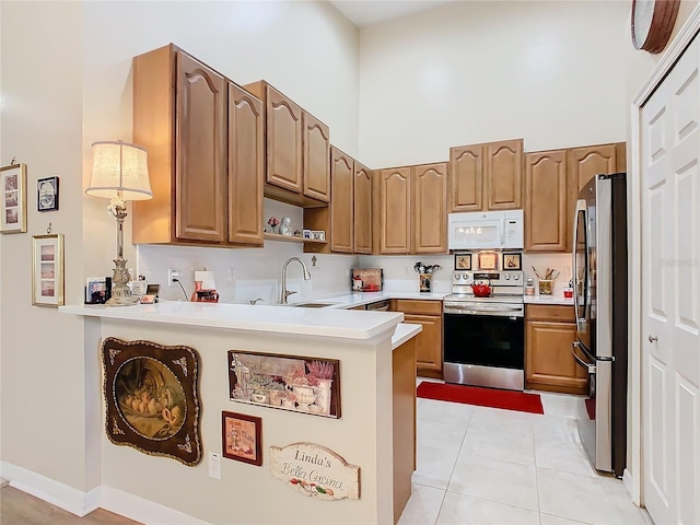 kitchen with a sink, a peninsula, stainless steel appliances, and light countertops