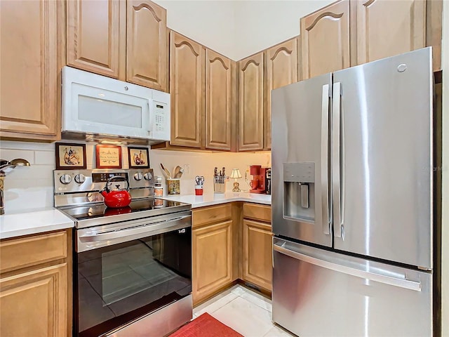 kitchen with appliances with stainless steel finishes, light countertops, decorative backsplash, and light tile patterned floors