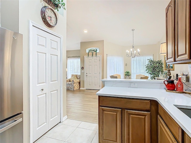 kitchen featuring brown cabinetry, freestanding refrigerator, and light countertops