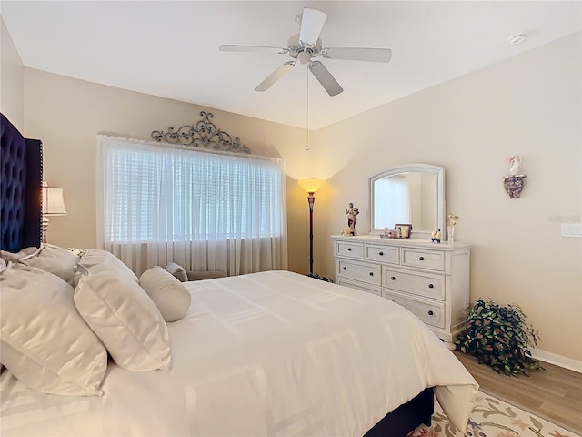 bedroom with light wood finished floors, ceiling fan, and baseboards