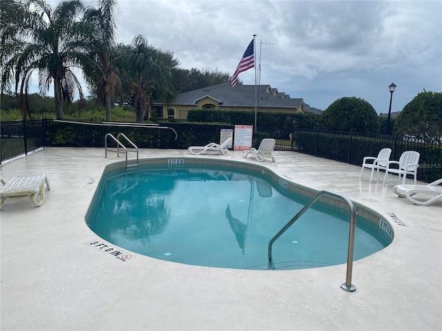 community pool with a patio area and fence