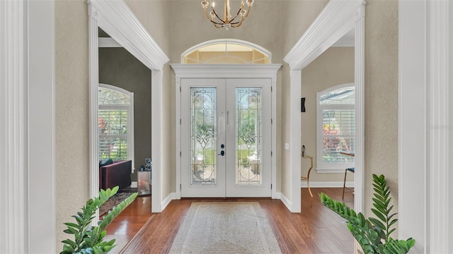 entryway featuring a chandelier, french doors, plenty of natural light, and wood finished floors