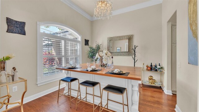 interior space with a healthy amount of sunlight, a notable chandelier, ornamental molding, and wood finished floors