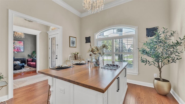 home office with baseboards, ornamental molding, wood finished floors, and a notable chandelier