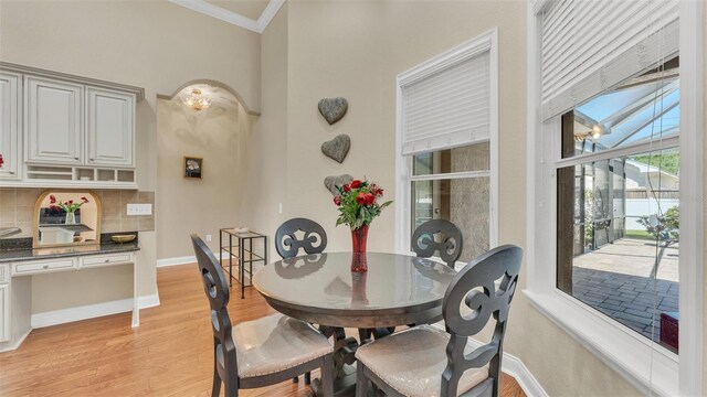 dining room with light wood-type flooring, baseboards, and crown molding