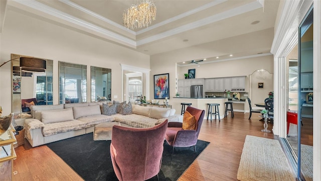 living room with a tray ceiling, crown molding, a towering ceiling, and wood finished floors