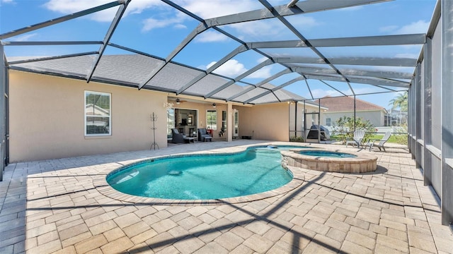 view of pool featuring glass enclosure, a patio area, ceiling fan, and a pool with connected hot tub