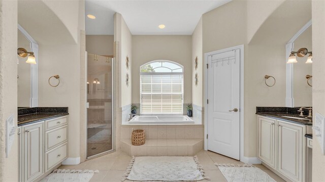 full bathroom with two vanities, a sink, a shower stall, and a garden tub