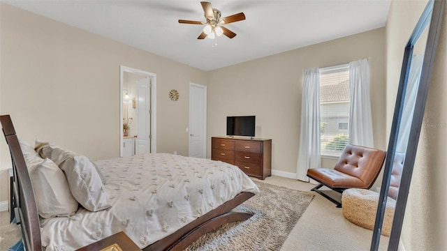 bedroom featuring light carpet, ensuite bath, baseboards, and ceiling fan