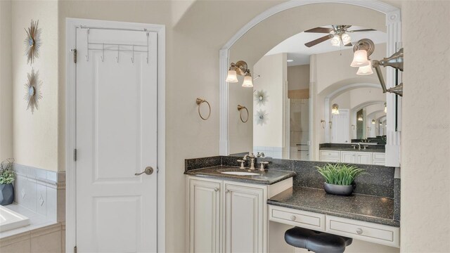 full bathroom with a ceiling fan, a garden tub, vanity, and walk in shower