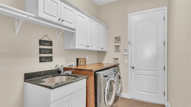 clothes washing area with washing machine and dryer, cabinet space, a sink, and baseboards