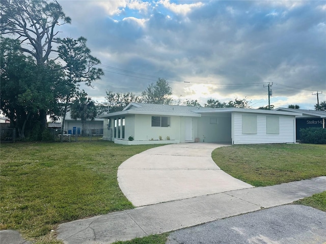 ranch-style house with concrete driveway, a front lawn, fence, and an attached carport