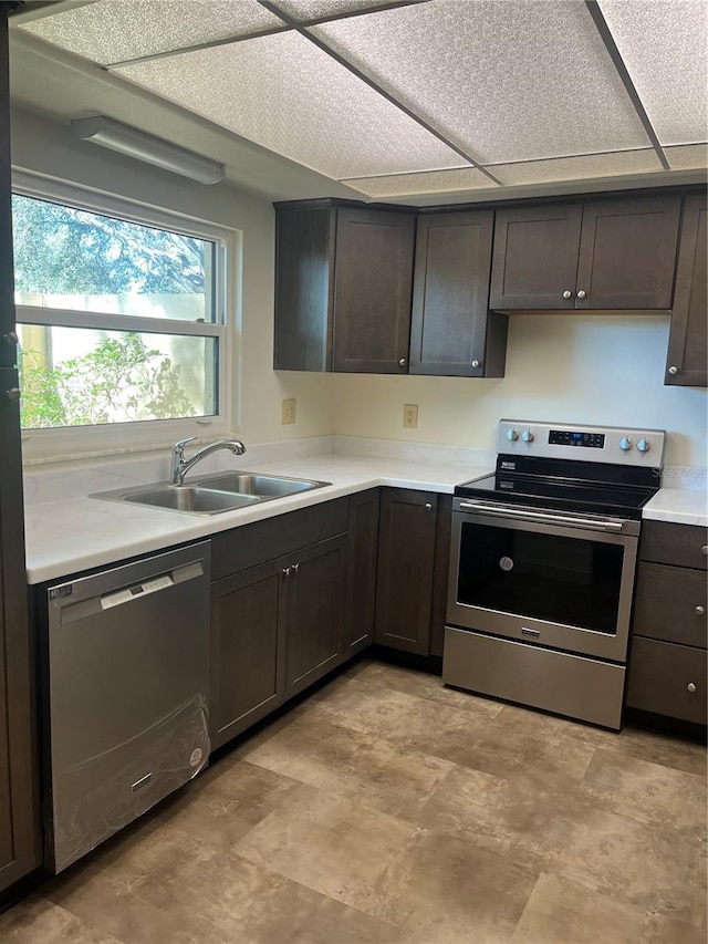 kitchen featuring light countertops, appliances with stainless steel finishes, a sink, and dark brown cabinetry