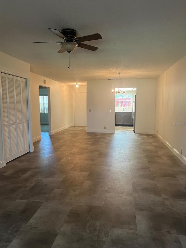 unfurnished room with baseboards and ceiling fan with notable chandelier