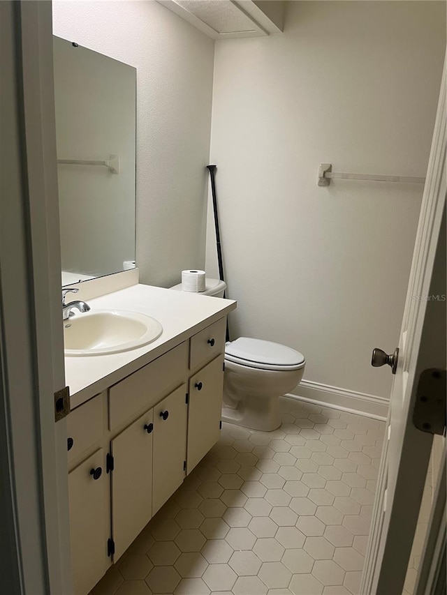 bathroom with toilet, baseboards, vanity, and tile patterned floors