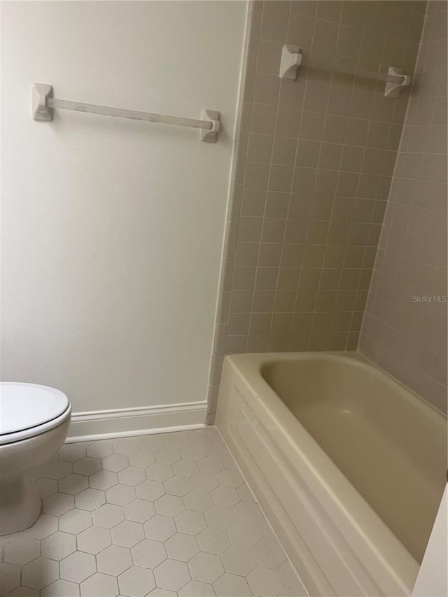 bathroom with toilet, baseboards, tub / shower combination, and tile patterned floors