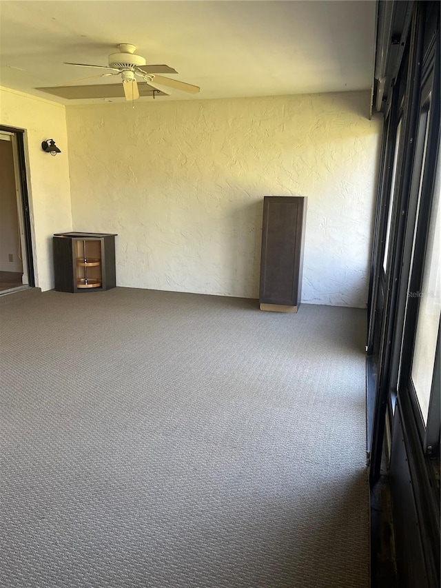 spare room with ceiling fan, a textured wall, and carpet flooring