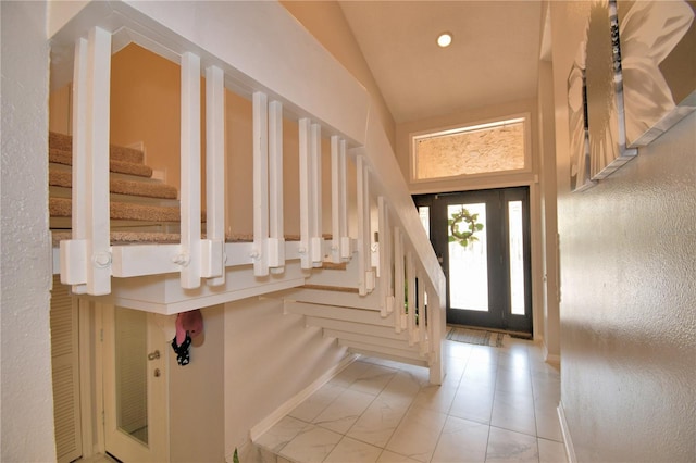 entryway featuring lofted ceiling, light tile patterned flooring, stairway, and recessed lighting