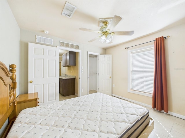 bedroom with visible vents, connected bathroom, baseboards, and light tile patterned floors