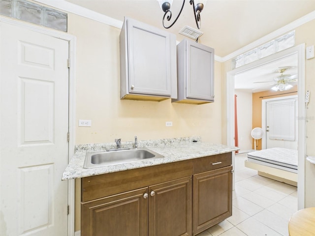 kitchen featuring visible vents, ceiling fan, ornamental molding, a sink, and light tile patterned flooring