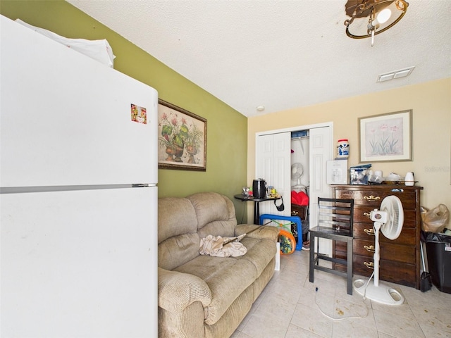 living room featuring visible vents, a textured ceiling, and light tile patterned flooring