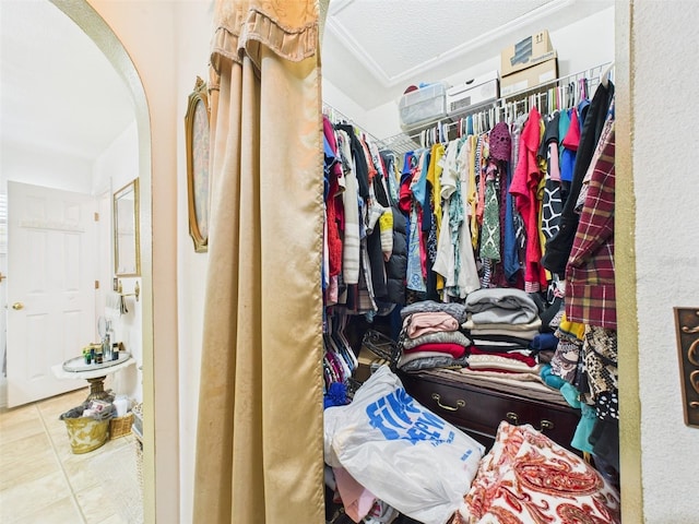 spacious closet featuring arched walkways and tile patterned floors