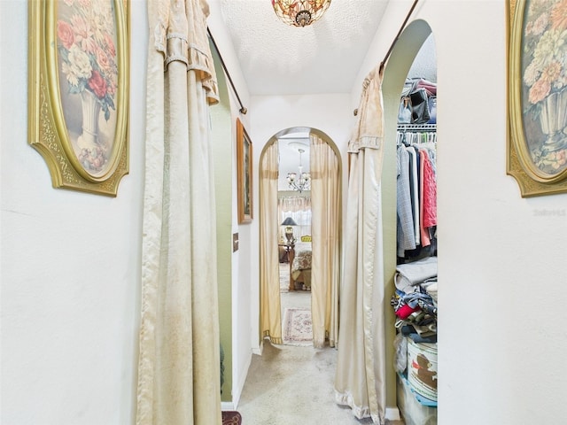 corridor featuring carpet, arched walkways, and a textured ceiling